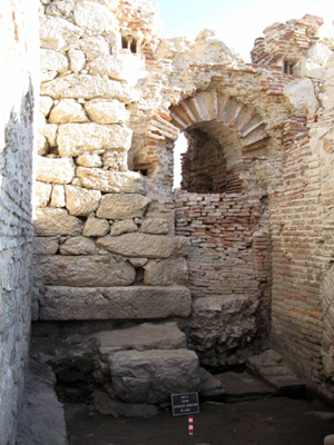 The approx. 3 metre high south wall of the heating room of the bathing complex. Warm air was blown under the floor of the middle apsidal space or &lsquo;caldarium&rsquo; (hot water pool). 
